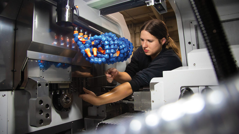 Emily Graven, an automation engineer intern at Absolute Machine Tools, shown here learning setup procedures on a Nexturn Swiss Machine.